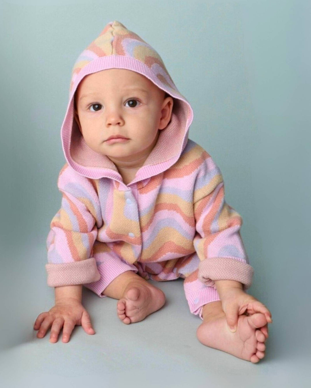 Baby sitzend in farbigem Strickstrampler